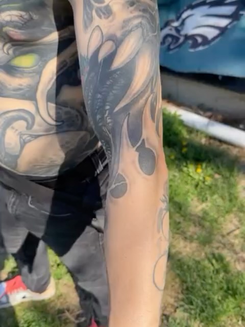 half-finished sleeve, black snake and skeleton over faded yellow-green wash with patches of unfilled skin and a small color rose
